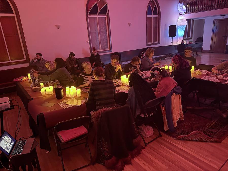 A full room of people collaging at candlelit tables inside Spire