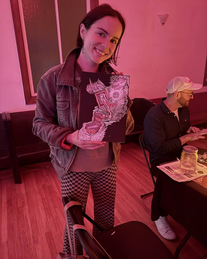 A guest smiling and holding up her finished scratch-art collage