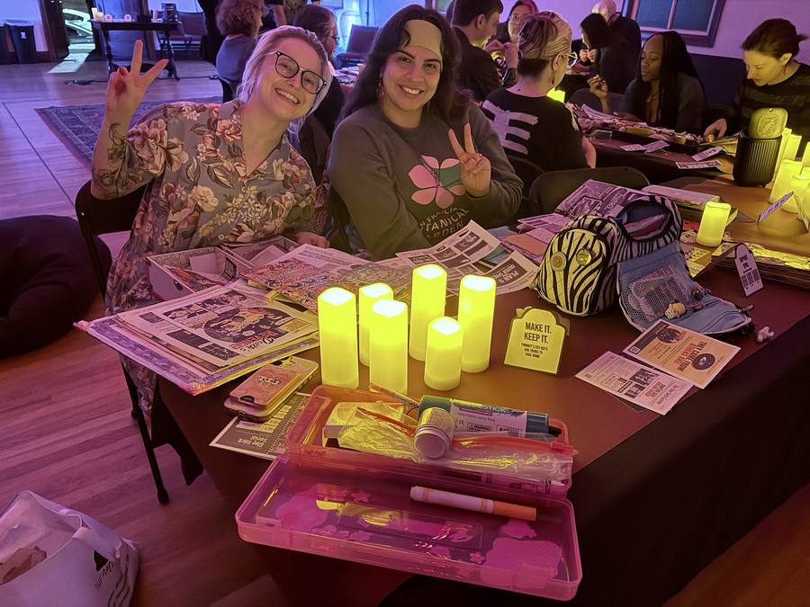 Two guests flashing peace signs over a table of cut-outs and candles